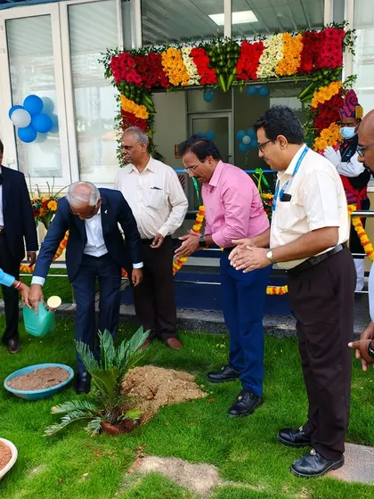 A wide shot of the celebratory planting, showing the festive atmosphere with floral decorations in the background of the newly landscaped area.