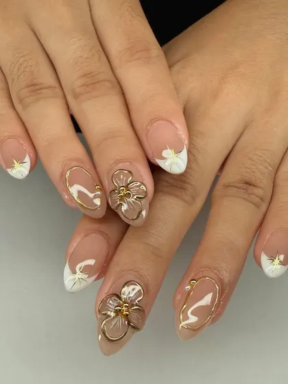 A beautiful combination of French tips and 3D art. This set features sculpted gold flowers and gold chrome outlines on a nude base.