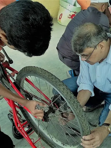 Roll up your sleeves and get your hands dirty. This is what active learning looks like. A participant and mentor work together on a bicycle wheel, showing the focus and teamwork that happens at our repair cafes.