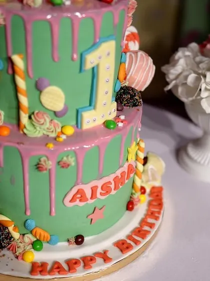 The colorful and delicious-looking Candyland cake, covered in lollipops, candies, and pink frosting drips. It perfectly matches the sweet and playful theme.