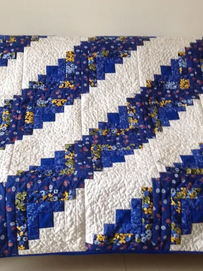 A "Log Cabin" quilt in a "barn raising" setting, using blue and white floral fabrics.