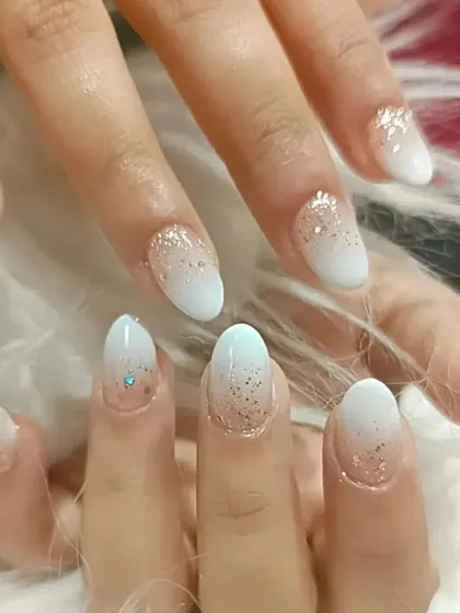 A glitter ombre design where a cascade of fine gold glitter fades into a soft, milky white tip.