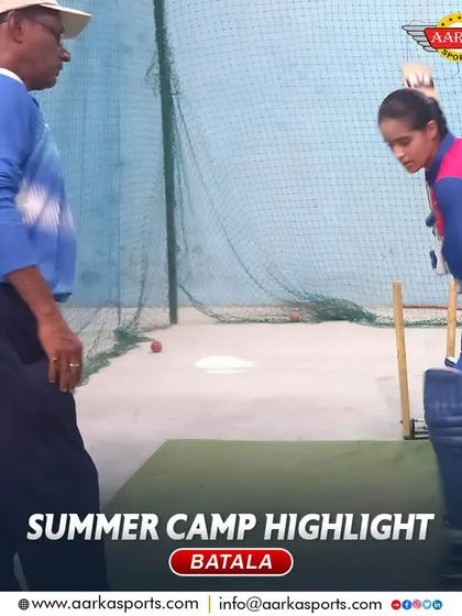 A female cricketer practices her batting stance under the watchful eye of a coach. Her focus and determination are commendable.