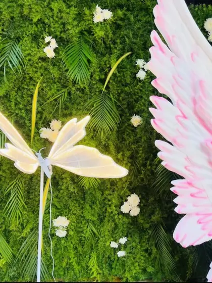 A close-up detail from a larger decoration, showing a lit butterfly element against a green wall with angel wings.