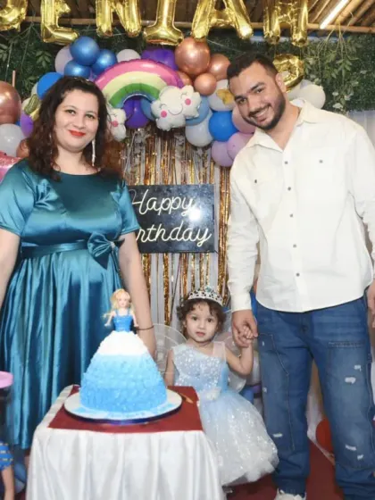 The family poses together before cutting the beautiful doll-themed birthday cake.