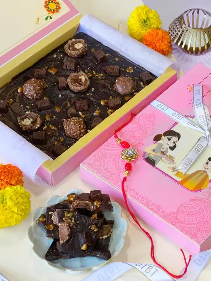 Here is my Chocolate Tile from the Raksha Bandhan 2023 collection. It's a slab of rich, dark chocolate loaded with Ferrero Rocher, brownie chunks, and crunchy nuts, presented in a festive pink box with a cute Rakhi tag.