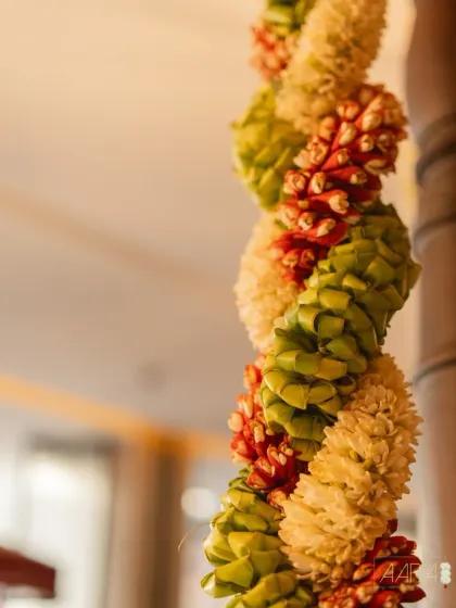 A close-up of a traditional South Indian garland, meticulously handwoven from coconut leaves, jasmine, and firecracker flowers. This type of detailed floral craftsmanship is a signature element I use to bring authenticity and beauty to wedding decor.