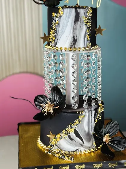 Pure elegance. This breathtaking black and gold chandelier cake is a true masterpiece, designed to be the luxurious centerpiece of a grand celebration.
