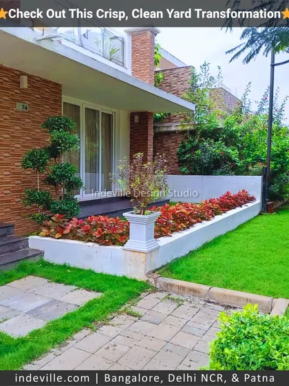 A front yard design featuring a raised planter bed with colorful coleus plants and a sculpted bonsai tree. The stone pathway and manicured lawn complete the formal and elegant look.