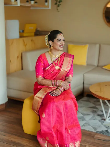 A beautiful portrait of the bride in her vibrant pink saree. The makeup is soft and natural, with a flush of color on the cheeks and a deeper lip to anchor the look.