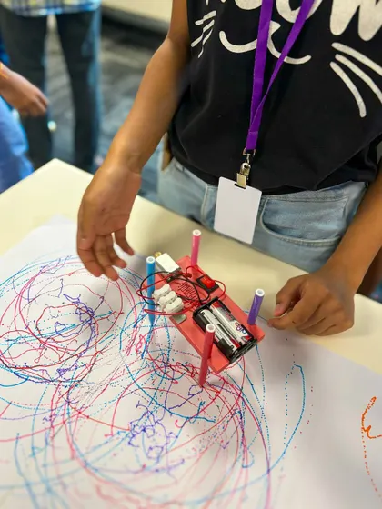 The pure joy of seeing your creation come to life. This student is watching their custom-built scribble bot create a unique piece of art, a project that combines basic electronics, motors, and a lot of imagination.