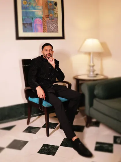 A stylish portrait of the groom seated in a modern chair, looking thoughtful and composed during his reception.