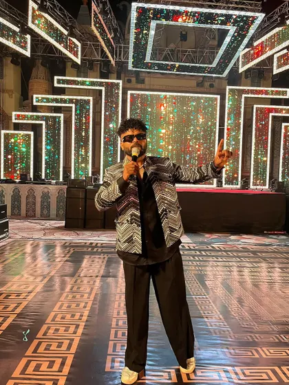 On stage, mic in hand, ready to take the Sangeet night to the next level. The grand stage setup adds to the spectacle.
