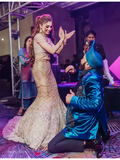 A fun moment on the dance floor, with a guest kneeling to dance with the bride.