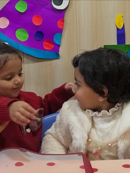 A candid moment of friendship as one child shares her treat with the birthday girl.