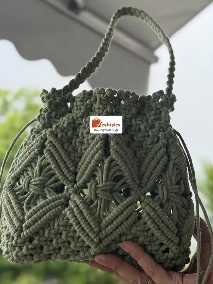 Holding the olive green potli bag to show its size. It's compact yet spacious enough for your phone, keys, and lipstick.