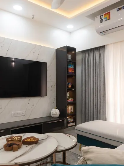 Another angle of the dreamy living room, focusing on the entertainment wall with its marble-finish panel and integrated vertical bookshelf.