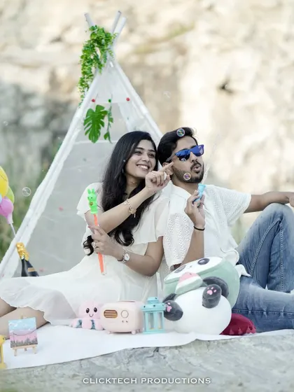 A fun picnic-themed pre-wedding shot, with a couple blowing bubbles and relaxing in a teepee tent setup.