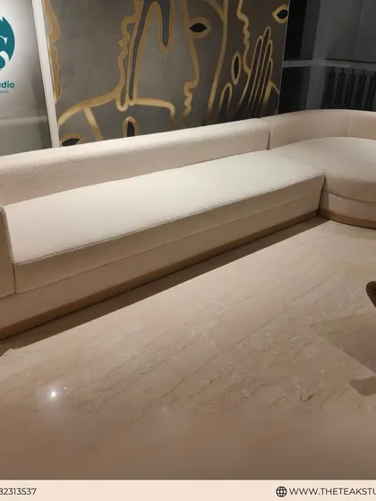 This custom L-shaped sofa features a unique curved chaise end, providing a soft and inviting seating area. Upholstered in a light, neutral fabric, it creates a sense of spaciousness and modern luxury.