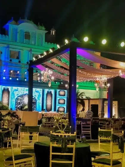 An outdoor Sangeet setup in Jaipur, with the venue beautifully illuminated in shades of blue and green.