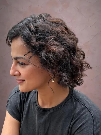 The highlights add dimension and depth to her curly bob.