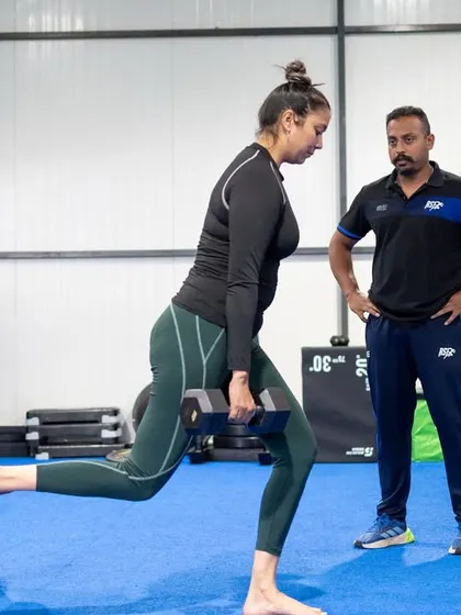 A client performs a Bulgarian split squat under the watchful eye of a coach. We focus on proper form to ensure our lifestyle athletes build strength safely and effectively.
