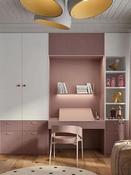 This modern study unit is perfect for a kid's room, featuring a pink and white color scheme with fluted panel details. The design integrates a desk, drawers, and a wardrobe into one cohesive piece.