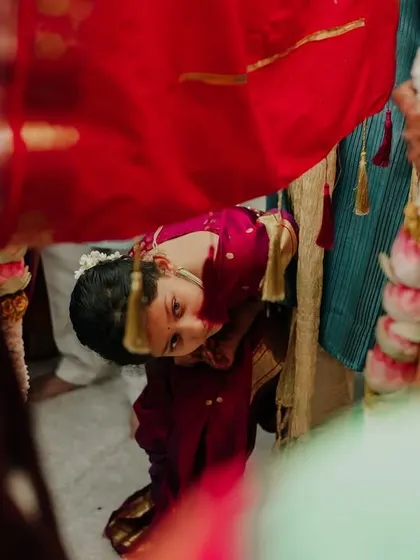 A child peeking from under the Antarpat during a Maharashtrian wedding. These curious, candid moments from the little guests add so much charm to the wedding album.