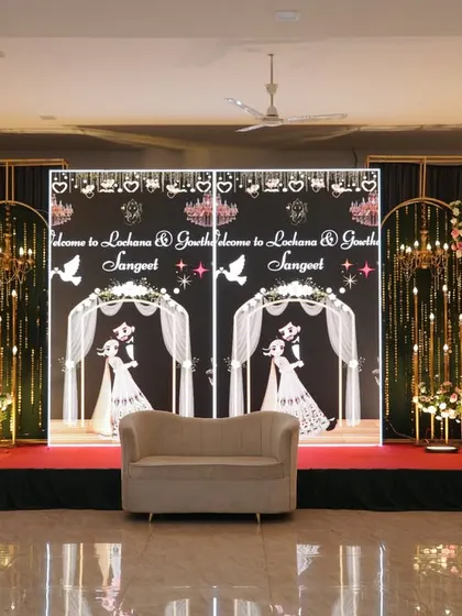 A unique Sangeet stage with custom graphic backdrops, framed by golden arches and chandeliers.