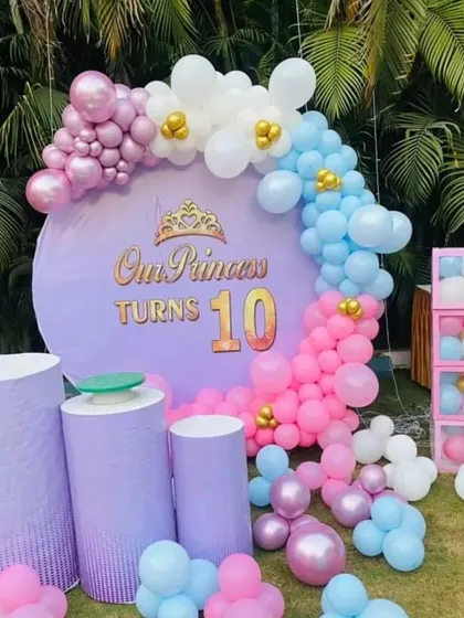 An outdoor "Our Princess Turns 10" party. This setup includes a large circular backdrop, pastel balloon arrangements, and display pedestals.