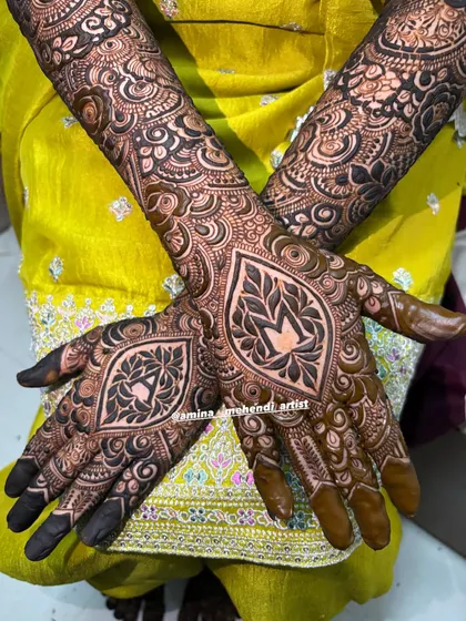 This design features bold, leaf-like motifs on each palm, with the initials 'A' and 'M' beautifully integrated inside. The surrounding patterns are intricate and detailed.