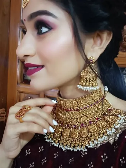 A side profile close-up of a different, more intricate temple choker with pearl droplets, paired with the same red velvet outfit.