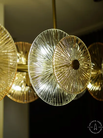 A linear chandelier featuring an arrangement of clear and amber-tinted textured glass discs. This fixture provides both direct and ambient light, adding a layer of sophistication and warmth to dining areas and boardrooms.