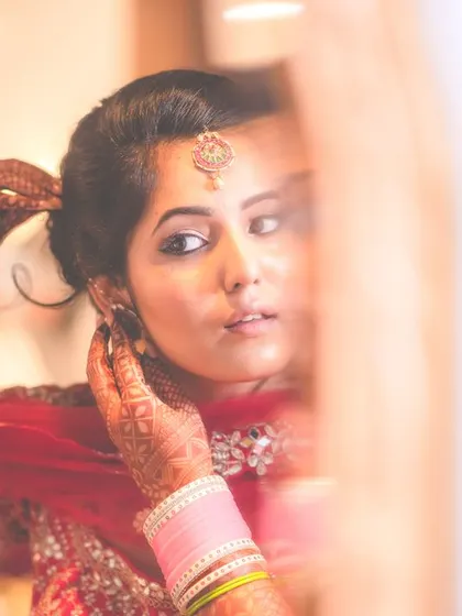 A candid shot of a bride getting ready, catching her reflection in the mirror. This intimate moment captures the final touches before she steps out for her big day.