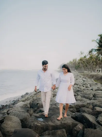 A couple enjoys a peaceful walk on the rocks by the sea.