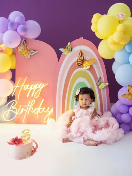 A beautiful rainbow and butterfly theme for this little girl's first birthday. The pastel balloon arch and neon sign create a magical backdrop for her special day.