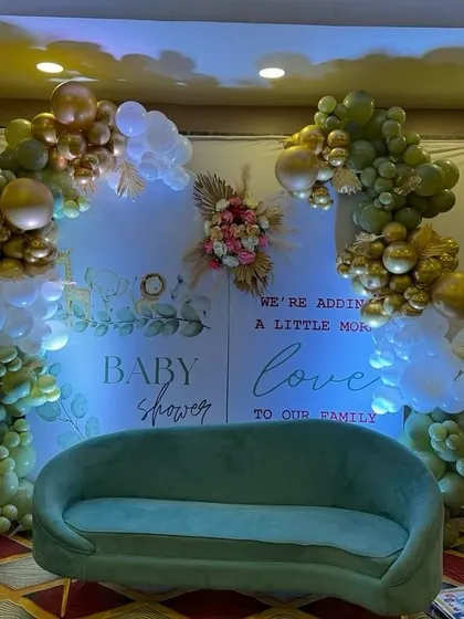 A wider view of the elegant baby shower setup, showing the green sofa placed for guests to take pictures.