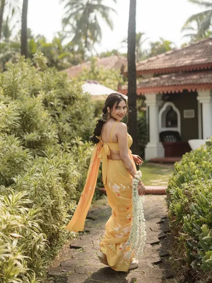 A beautiful shot of the bride in her yellow Haldi saree, looking back with a smile.