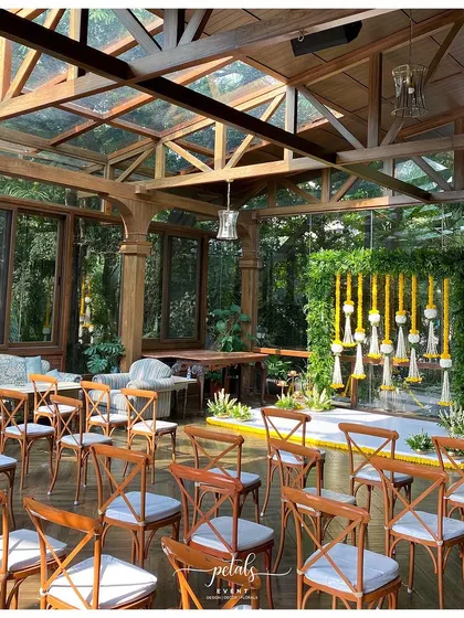 The engagement ceremony setup in a beautiful glasshouse venue. The fern frame and floral streamers look stunning against the natural backdrop.