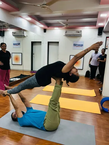 I demonstrate the base position in Acro Yoga, supporting a student in a graceful plank pose. Safety and proper technique are my top priorities in these sessions.