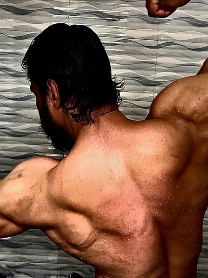 A back double biceps pose, showing the peak and width of my arms and back. This is the result of consistent growth.