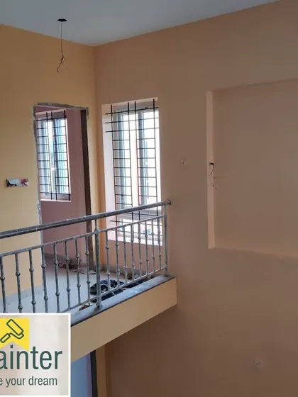 A hallway and landing area in a duplex house painted in a warm beige color. This neutral tone provides a seamless flow between floors.