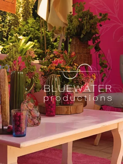 A close-up of a tabletop with vibrant pink decor, including fresh raspberries and unique floral arrangements.