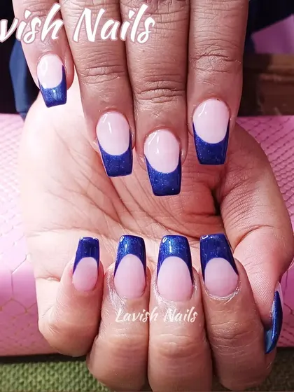 A bold French manicure with deep blue glittery tips on square-shaped nails.