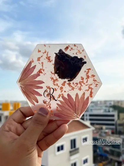This personalized coaster features a preserved rose and daisy petals, along with the initial 'R'. It’s a wonderful way to keep a piece of a special memory on your desk or coffee table.
