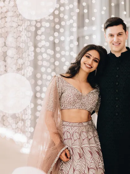 A glamorous couple poses against a backdrop of beautiful bokeh lights at their evening reception.