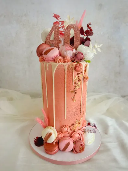This extra-tall rose gold drip cake was for a fabulous 40th anniversary. I layered it with macarons, fresh florals, and a touch of gold leaf to create a sophisticated and celebratory dessert.