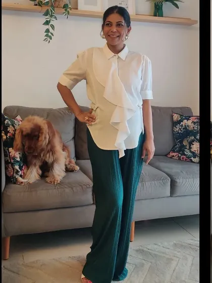 This full-length view showcases a complete bump-friendly outfit that is stylish and modern. The flowy top and pleated pants are pieces you can wear long after your pregnancy.