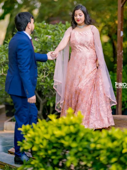A candid, romantic moment in a garden. The groom leading the bride by the hand creates a beautiful, unscripted feel.
