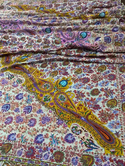 A wide shot capturing the magnificent spread of the Kashmiri Kalamkari dupatta, with its large, dramatic paisley motifs rendered in rich yellows and purples.